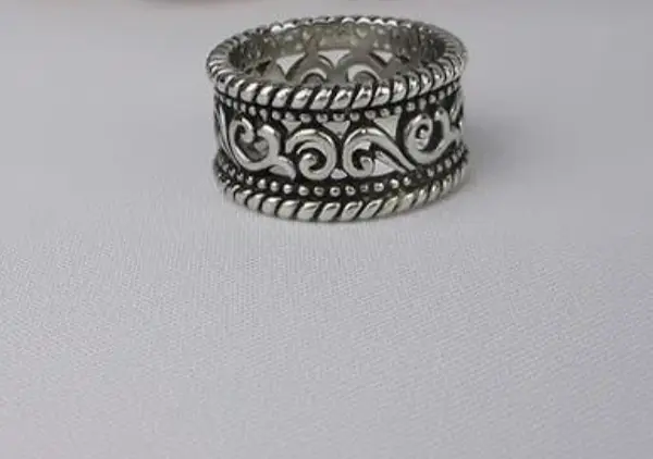 Silver ring with intricate design on a gray background