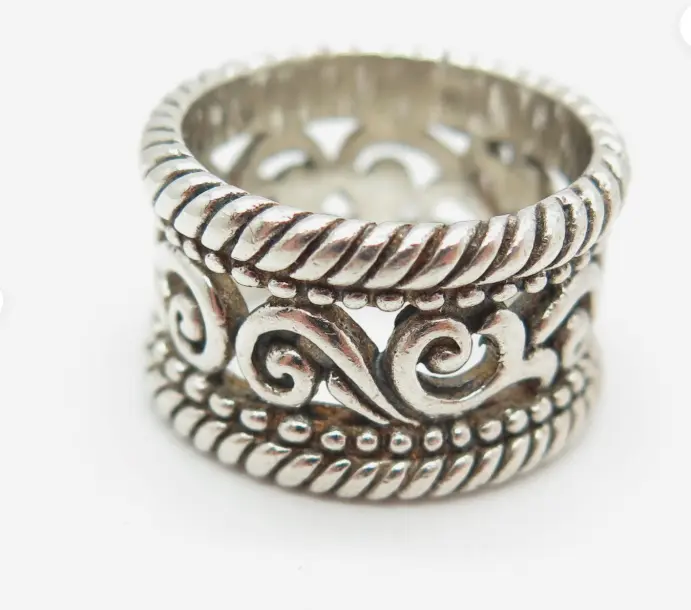 Silver ring with intricate designs on a white background