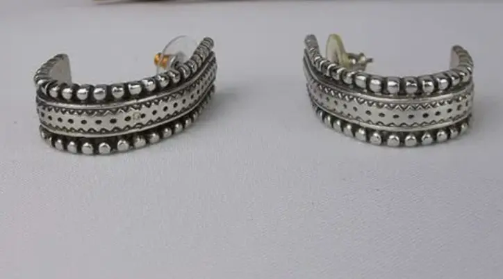 Pair of silver cuff earrings on a light gray background
