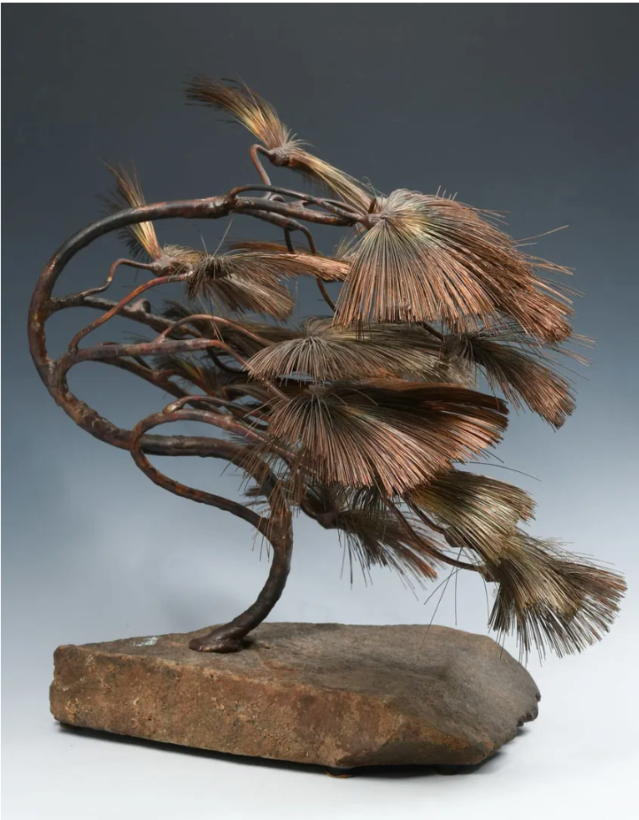 John Steck's copper and stone bonsai sculpture showcasing intricate fronds against a natural stone base.