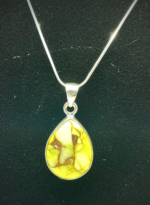 Teardrop-shaped amber pendant on a silver chain against a black background