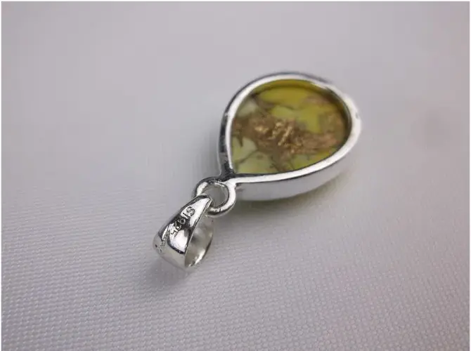 Silver pendant with a honey dahlia  on a gray background