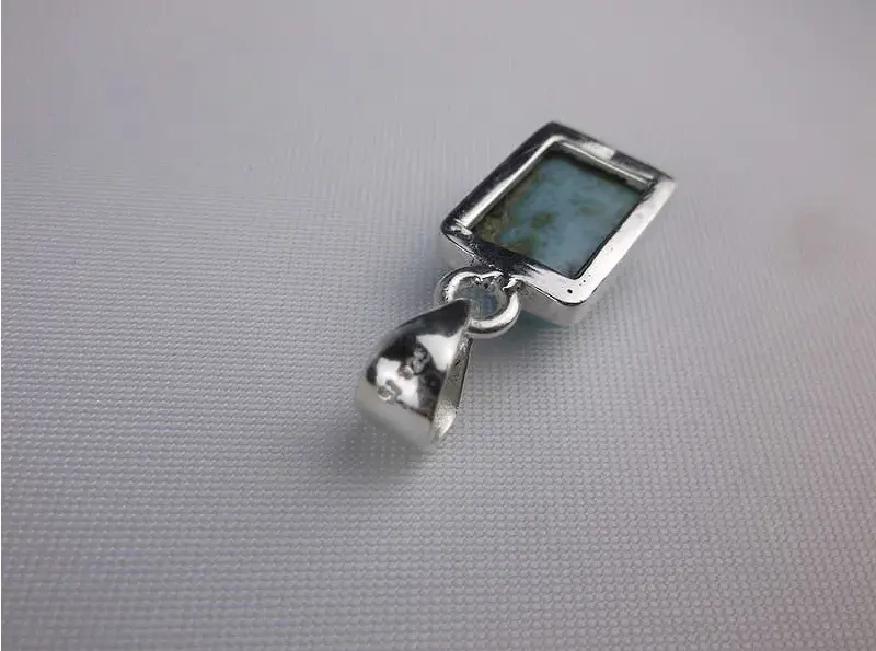 Silver pendant with a rectangular stone on a gray background